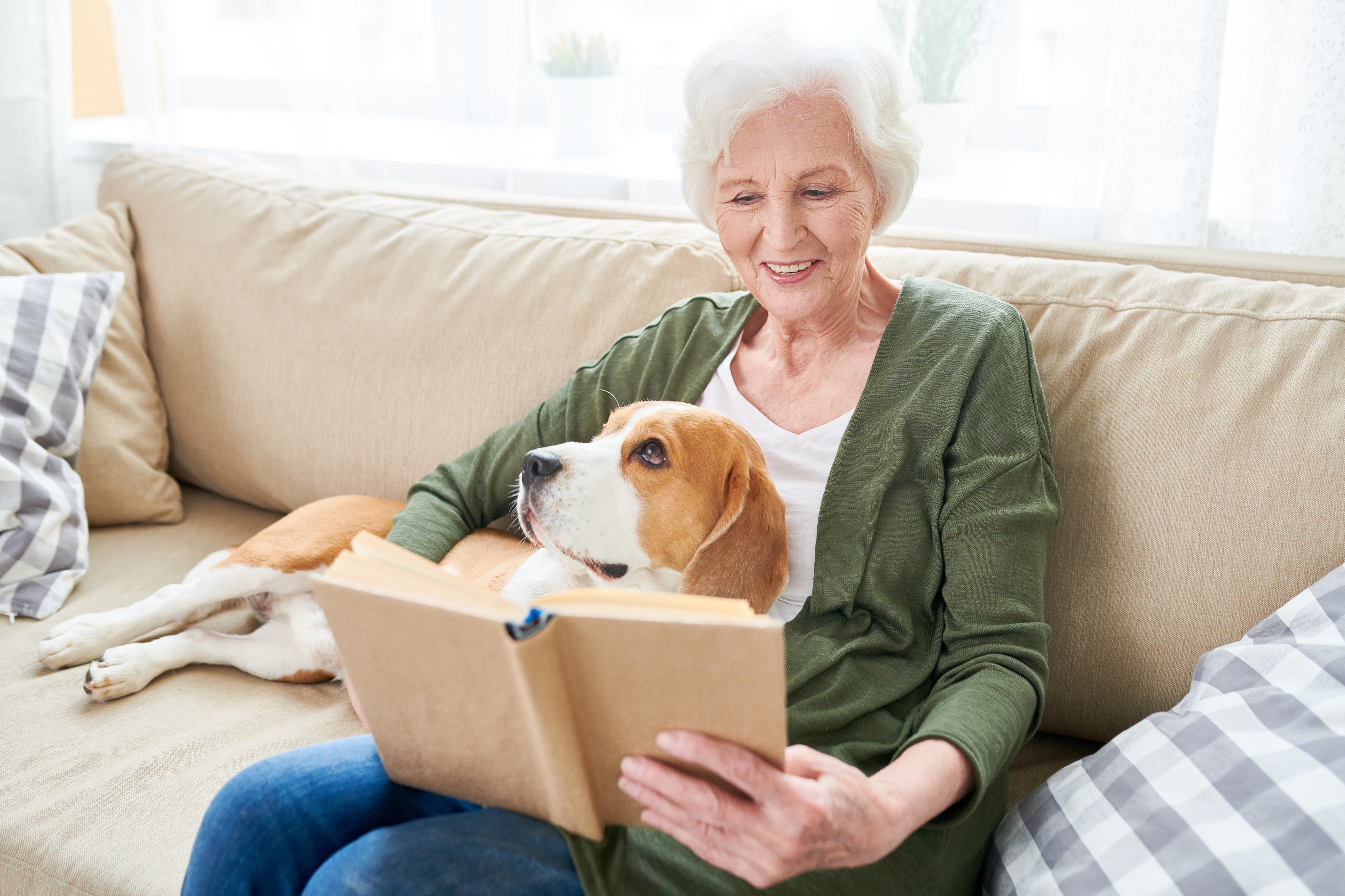 Senior woman relaxing on couch with dog while reading