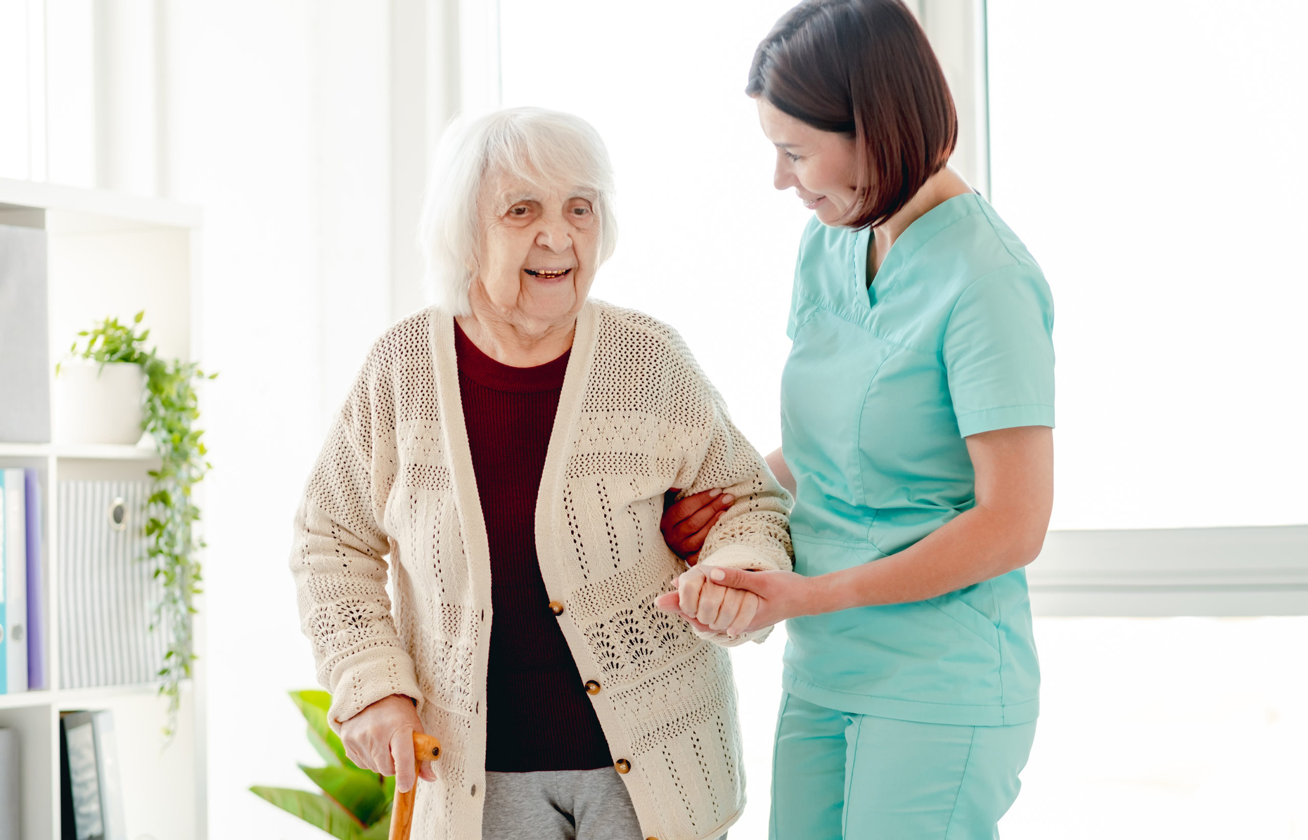 Caregiver helping elderly woman to walk